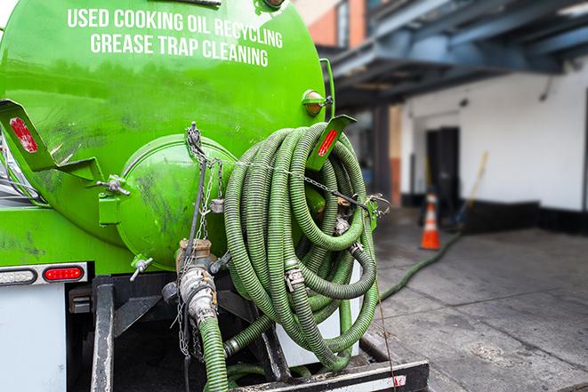 a technician pumping a grease trap in a commercial building in Rescue